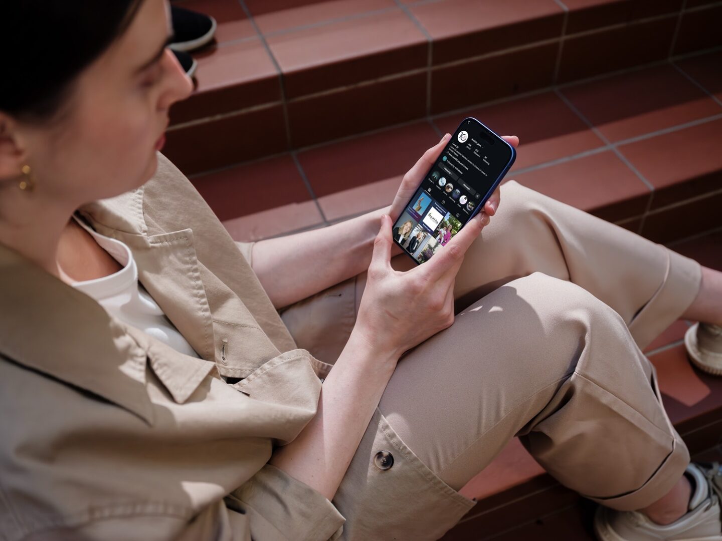 Mockuuups Iphone 16 Mockup Held By A Woman On Outdoor Steps (1)